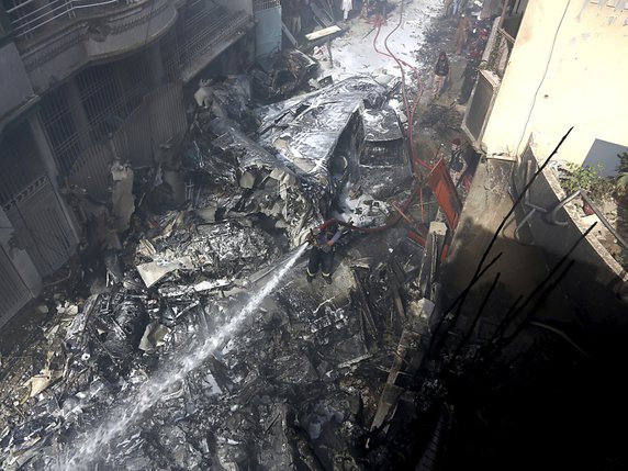 Des pompiers tentaient d'éteindre les débris de bâtiments d'un quartier résidentiel à Karachi au Pakistan où un avion de ligne s'est écrasé. © KEYSTONE/AP/Fareed Khan