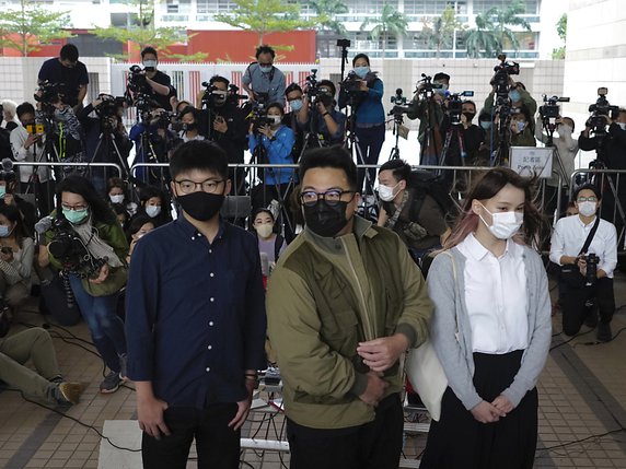 Joshua Wong, Ivan Lam et Agnes Chow, de gauche à droite, sont poursuivis pour une manifestation interdite devant le quartier général de la police de Hong Kong. © KEYSTONE/AP/Vincent Yu