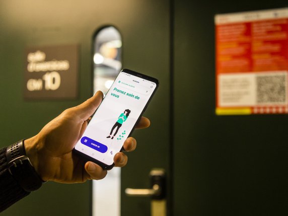 Une personne scanne avec son smartphone un QR-Code grâce à l'application NotifyMe, une nouvelle app pour identifier des lieux à risque d'infection du Covid-19 devant une classe du campus de l'EPFL. © Keystone/JEAN-CHRISTOPHE BOTT