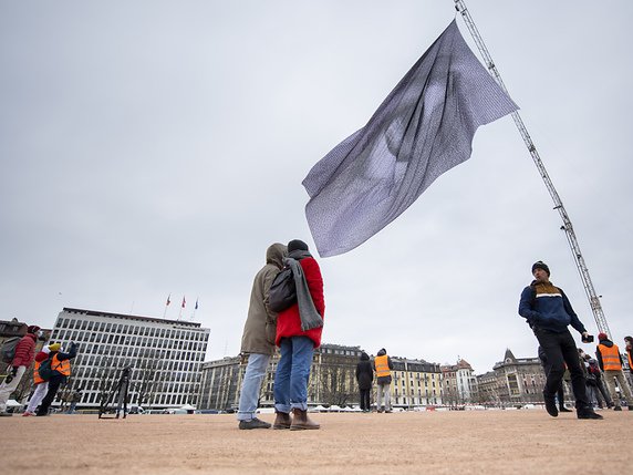 A Genève, un oeil géant flotte au-dessus de la plaine de Plainpalais pour alerter les dirigeants sur l'urgence climatique. Ce drapeau de 20 mètres sur 30 est constitué de 13'250 portraits photographiques et messages de 190 pays. © KEYSTONE/MARTIAL TREZZINI