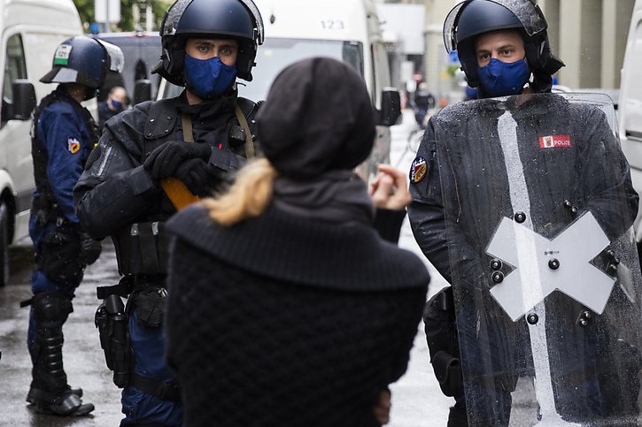 Une manifestante discute avec des policiers près de la Place fédérale. © KEYSTONE/PETER KLAUNZER