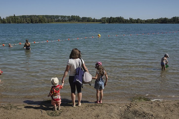 Une femme et ses enfants en quête de rafraîchissement dans un petit lac près de Lyon. © KEYSTONE/AP/Laurent Cipriani