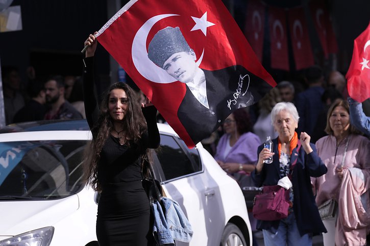 Les Turcs se pressent aux urnes dès l'aube dimanche, alors qu'une supportrice de l'outsider Kemal Kilicdaroglu brandit un drapeau à l'effigie du fondateur de la Turquie moderne Mustafa Kemal Ataturk. © KEYSTONE/AP/Burhan Ozbilici
