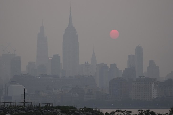 New York City dans un brouillard orange dû aux lointains incendies canadiens. © KEYSTONE/AP/Seth Wenig